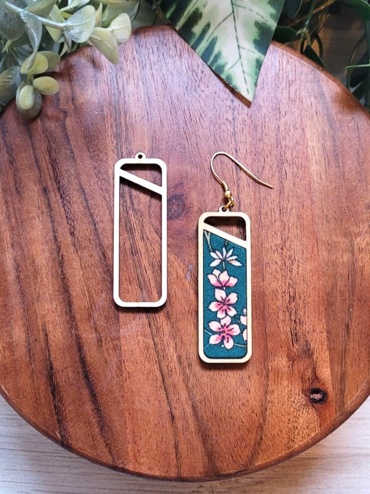 Image shows a rectangle shaped wooden frame and an earring made of fabric and the frame. The fabric is teal and has small pink and white flowers in a vertical row.  